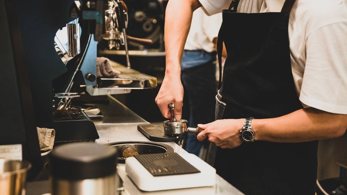 Người đang pha cà phê bằng máy pha cà phê tự động tại nhà